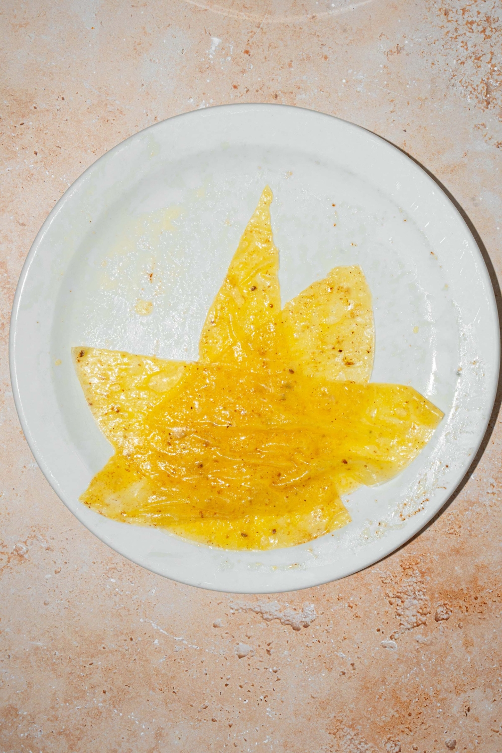 A white plate with three rice paper wrappers sliced into triangles, layered on one another. The plate is on a tan counter.