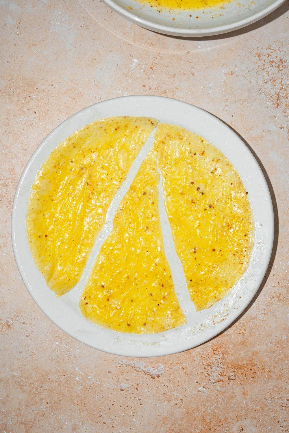 A white plate with rice paper soaked. in egg custard sliced into triangles. The plate is on a tan counter.