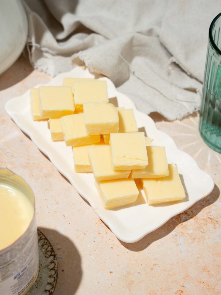 A white tray with pieces of vanilla fudge. The tray is on a tan counter with a white cloth napkin.