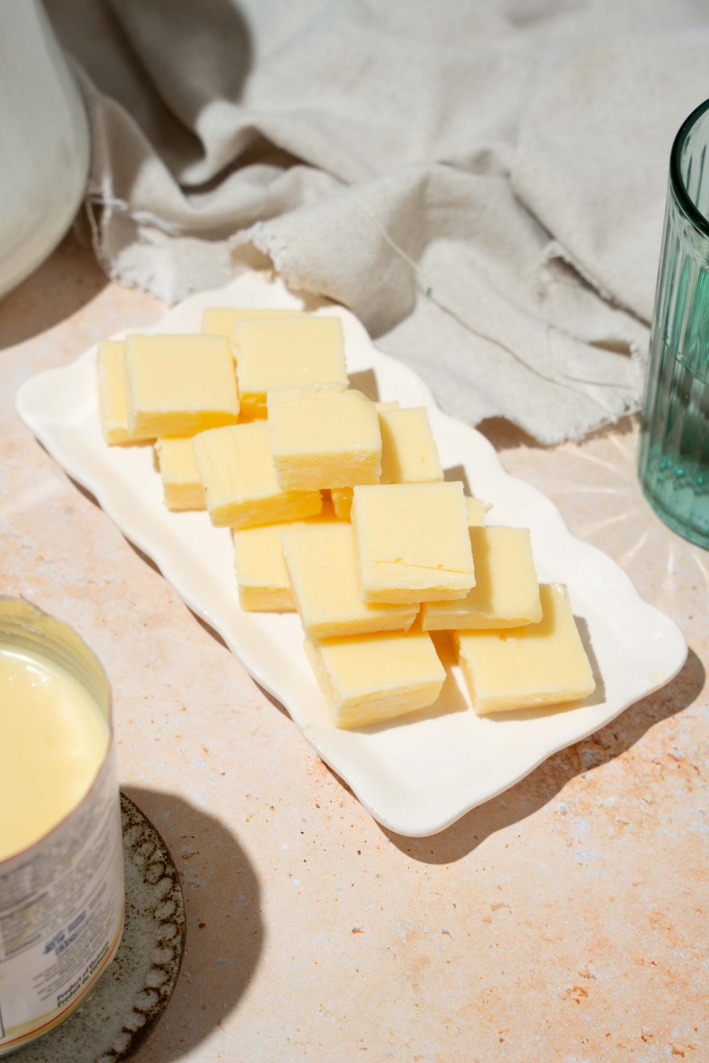A white tray with pieces of vanilla fudge. The tray is on a tan counter with a white cloth napkin.