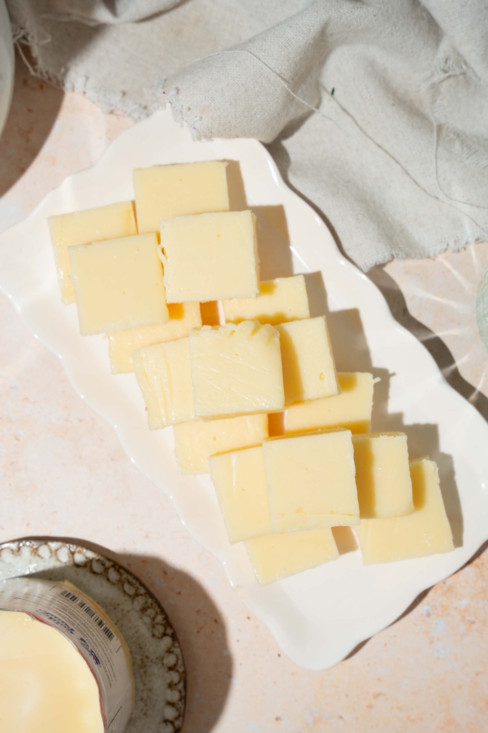 A white tray with pieces of vanilla fudge. The tray is on a tan counter with a white cloth napkin.