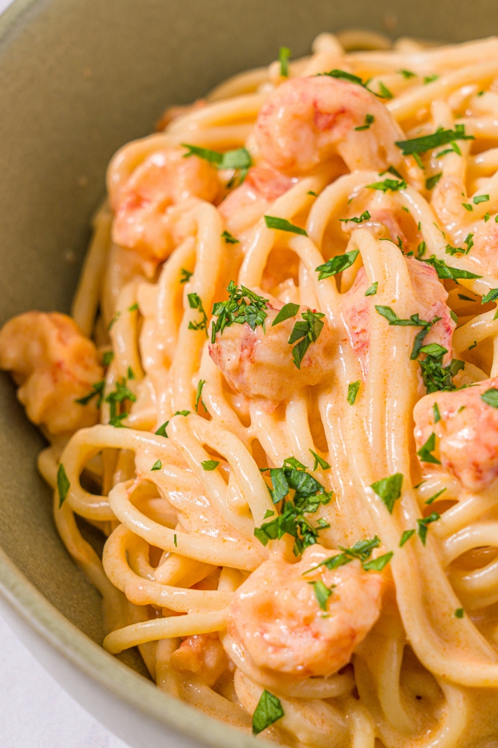 A bowl of Trader Joe's lobster bisque pasta garnished with fresh parsley.