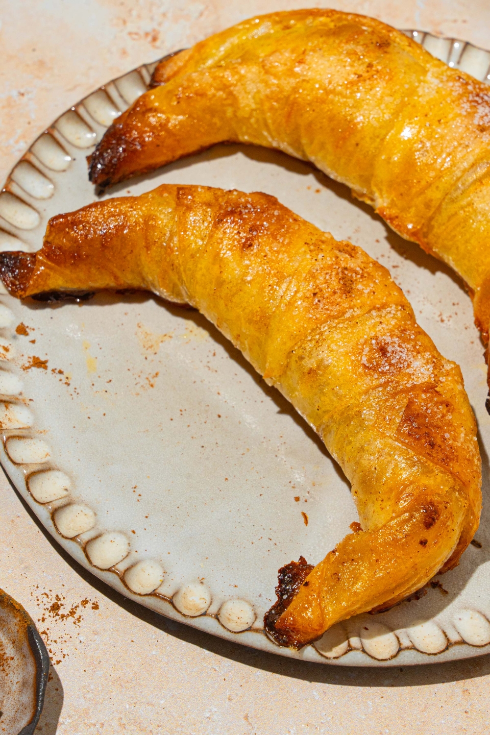 A plate with two baked rice paper croissants. The plate is on a tan counter.