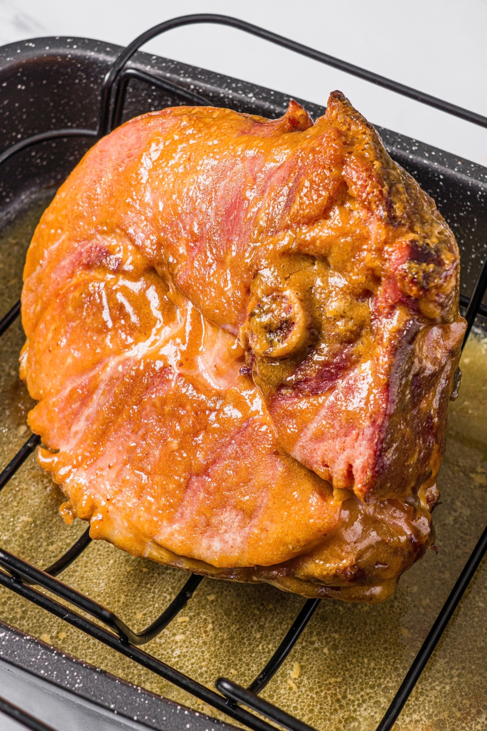 A baked ham shank in a roasting pan.