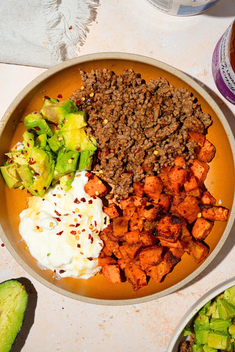 Hot honey, drizzled on top of sliced avocado, ground beef, diced, roasted sweet potatoes, and cottage cheese all in a bowl.