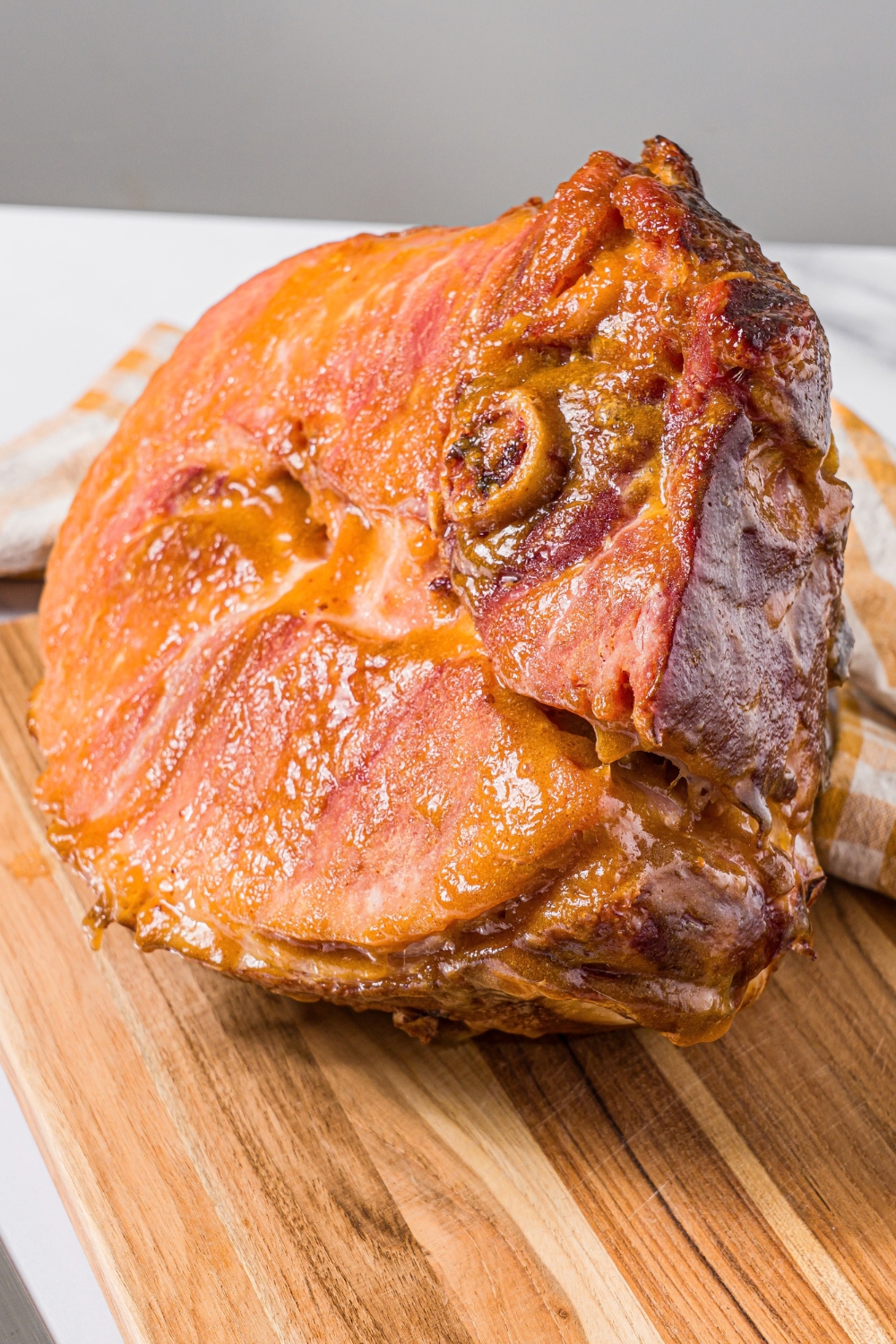 A baked ham shank on a wooden cutting board.