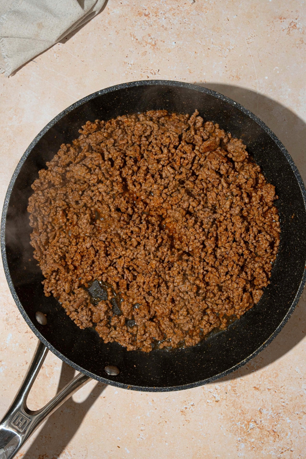 A skillet that is filled with brown ground beef.