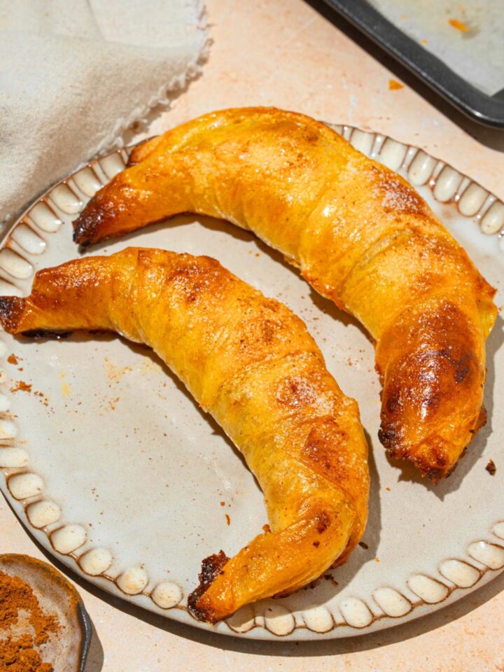 Two rice paper croissants on a white plate that is on a white counter.