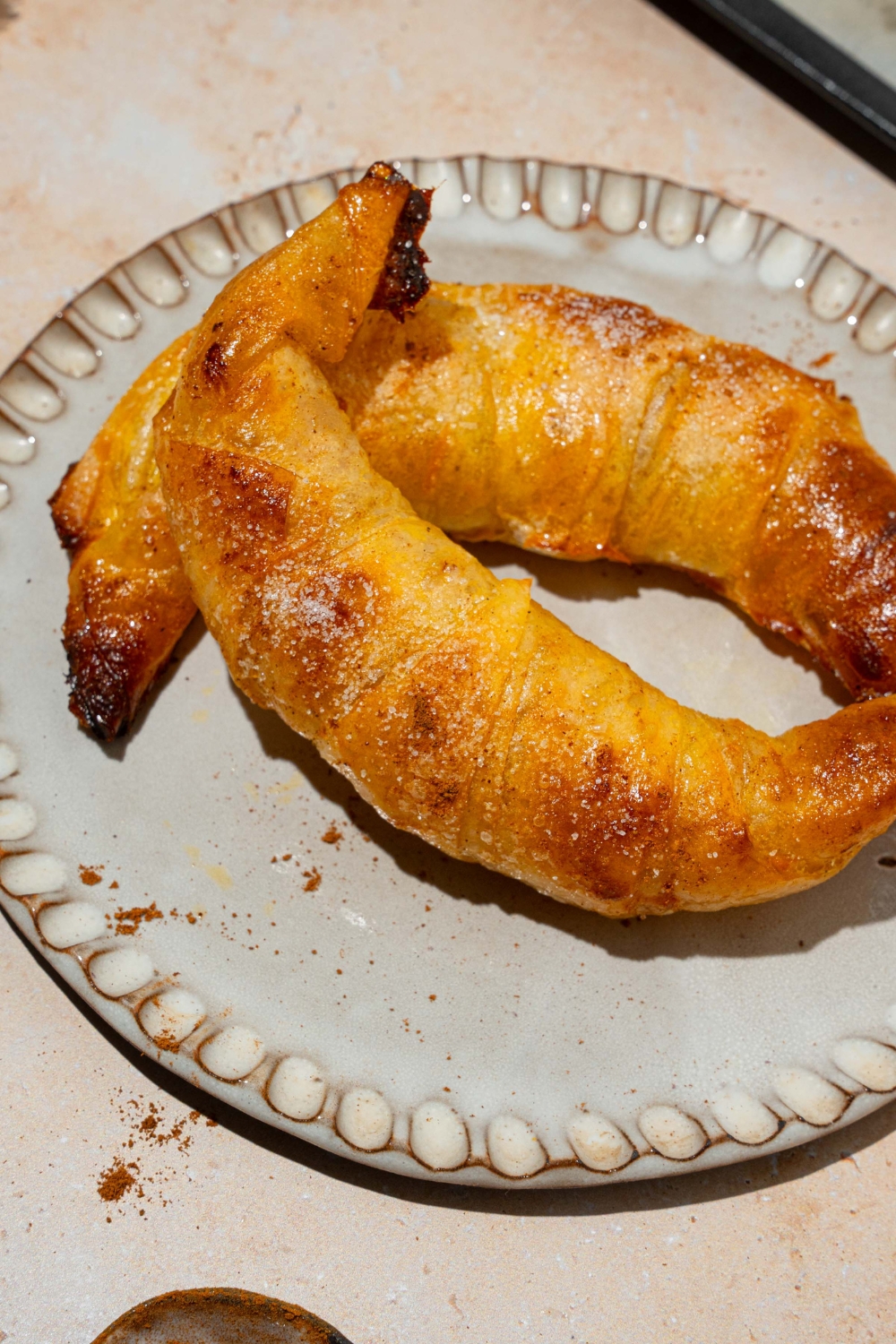 A plate with two baked rice paper croissants. The plate is on a tan counter.