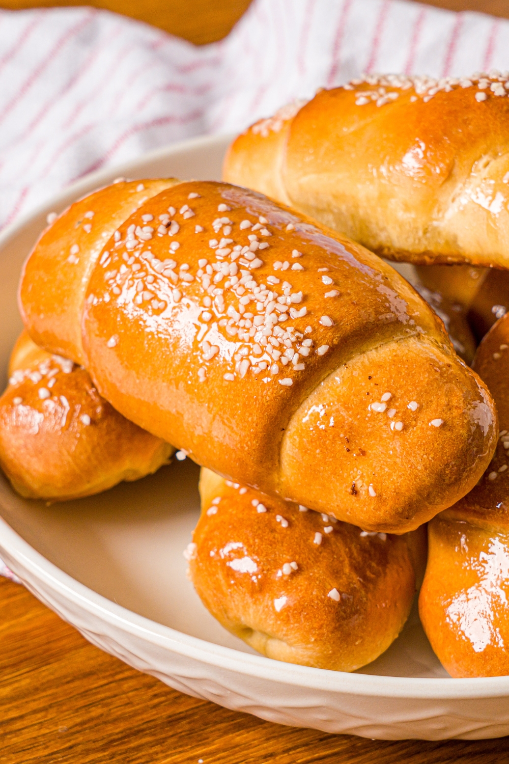A piece of salt bread on top of a few more pieces of salt bread on a white plate.