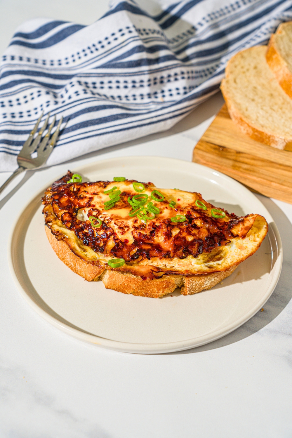 Hot honey eggs on top of a piece of sourdough toast on a white plate.