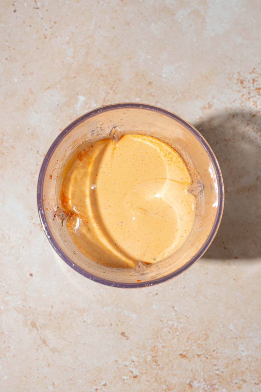 A small bowl of mixed high protein Buffalo sauce. The bowl is on a tan counter.