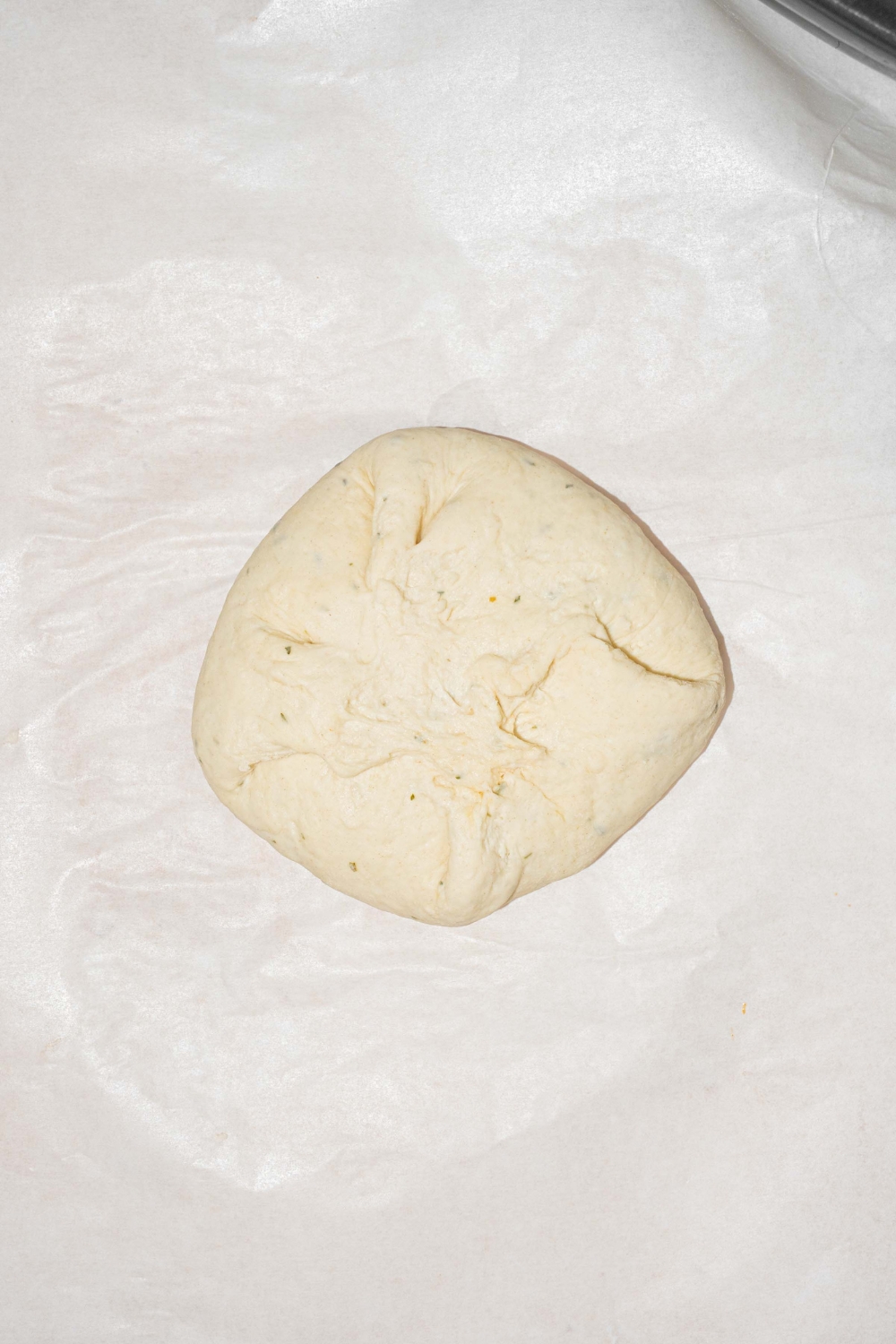 A piece of parchment paper with a folded uncooked Buffalo chicken hot pocket.