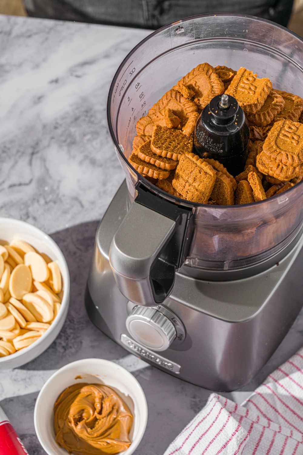A food processor filled with Biscoff cookies. The food processor is on a marble counter.