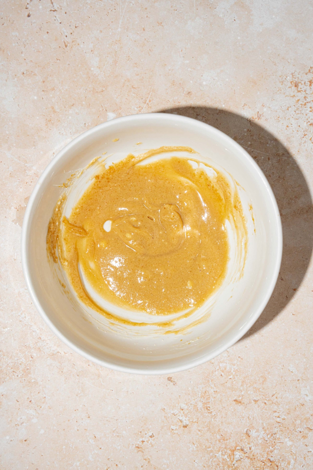 A large bowl with a brown sugar and cream cheese mixture. The bowl is on a tan counter.