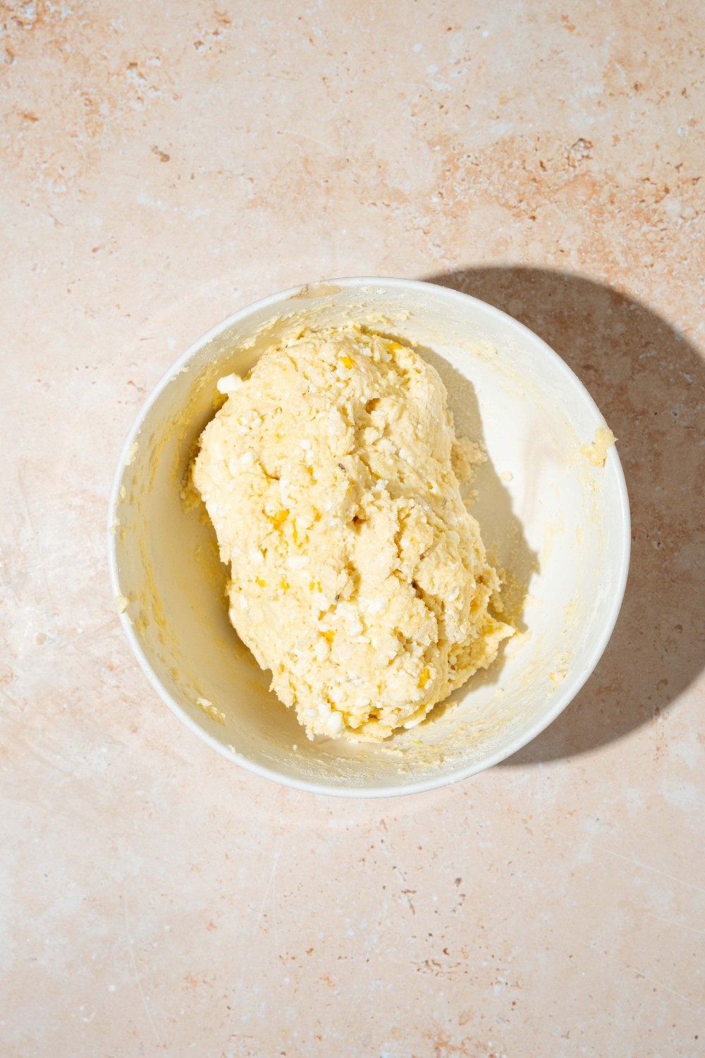 A white bowl with cottage cheese breadstick dough mixture. The bowl is on a tan counter.