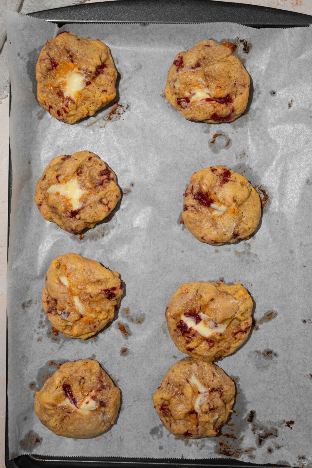 A baking sheet lined with parchment paper with baked strawberry cheesecake cookies.