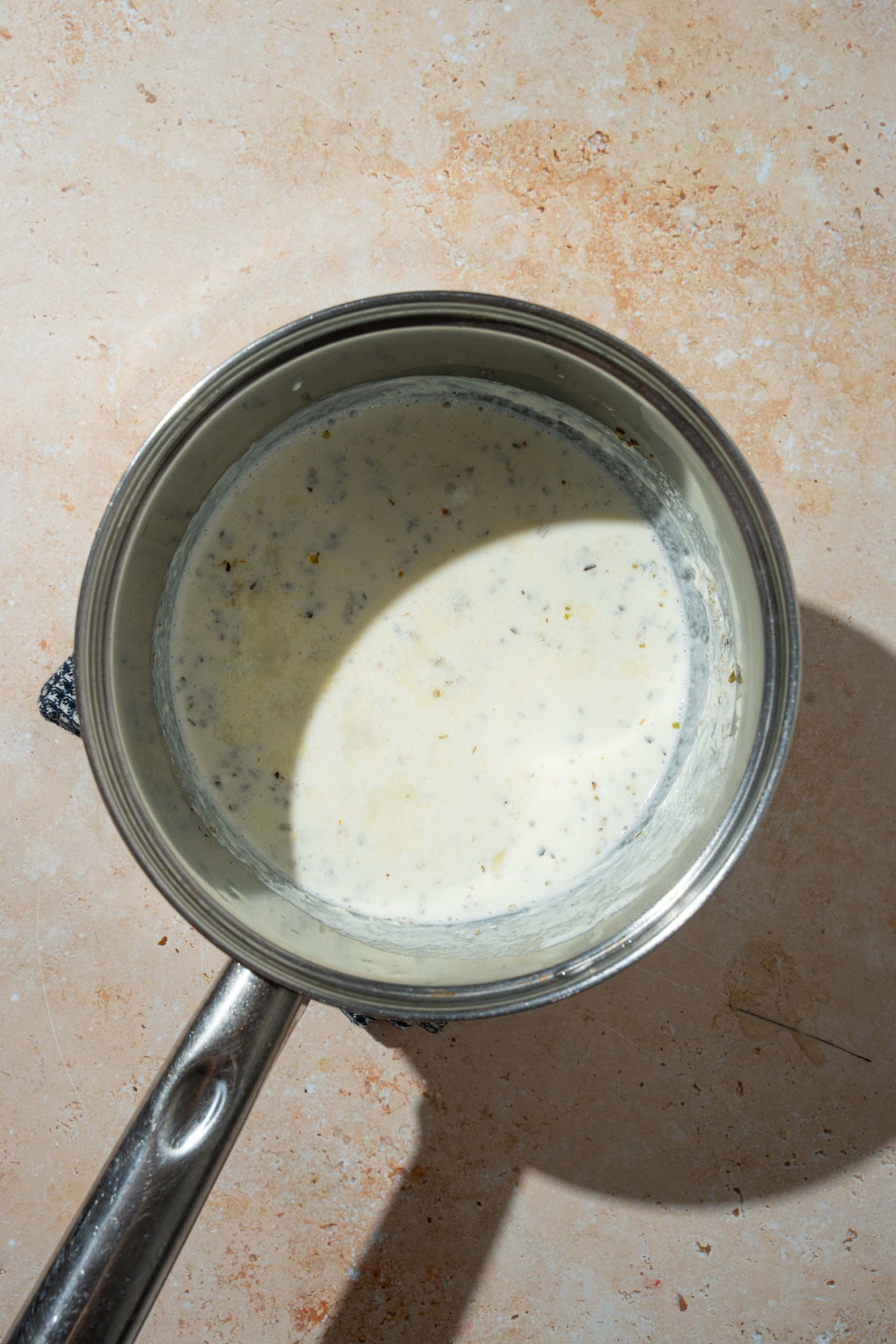 A stock pot with cream sauce for potato pave. The pot is on a tan counter.