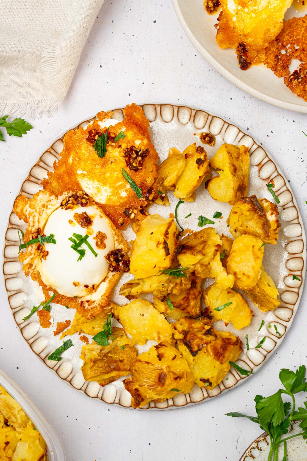 Two crispy feta eggs and potatoes on a white plate.