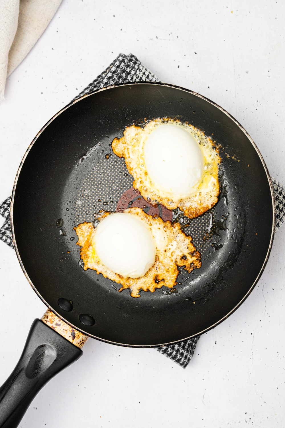 Two jammy eggs on top of crispy feta in a black skillet.
