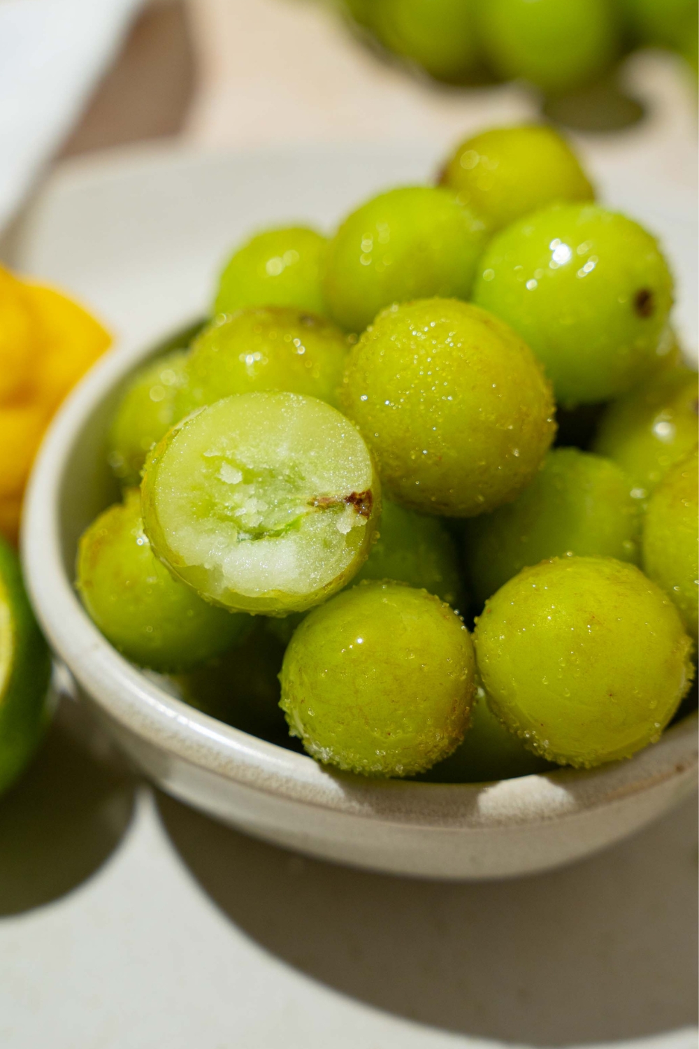 Frozen sour grapes on top of one another in a white bowl.