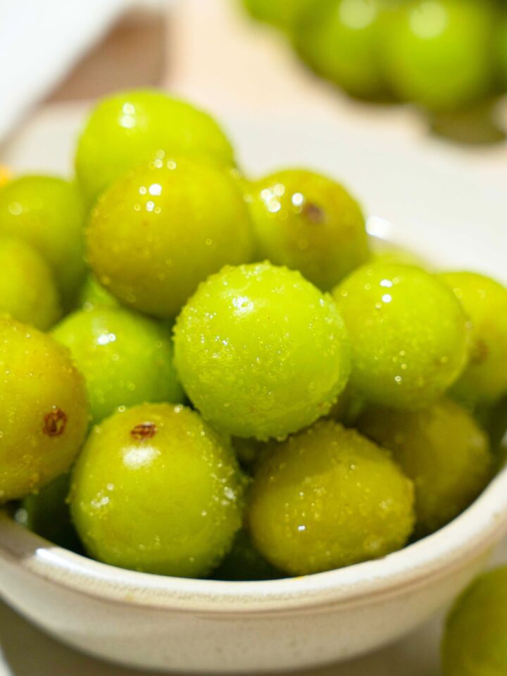 A white bowl with a bunch of frozen sour patch grapes in it.