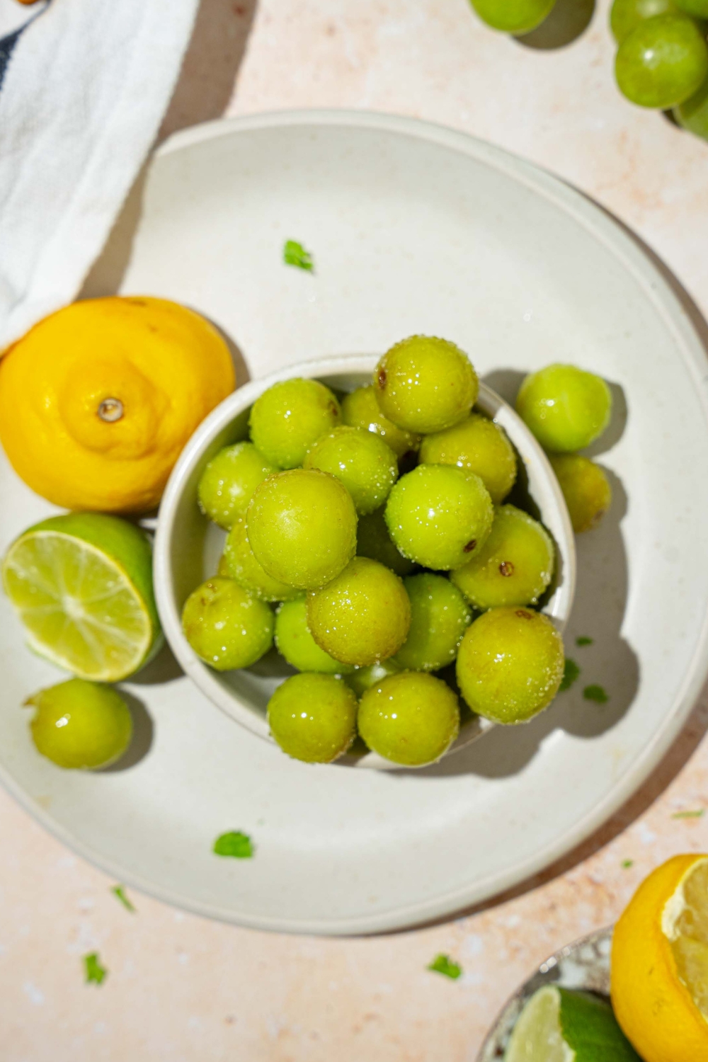 A bunch of frozen grapes on top of one another in a white bowl on top of a white plate.