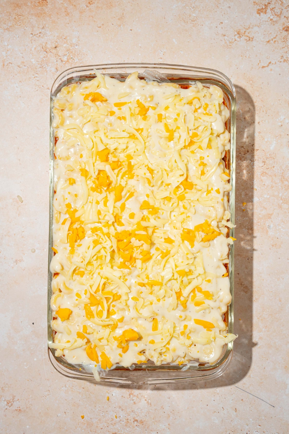 Unbaked mac & cheese lasagna in a glass baking dish.