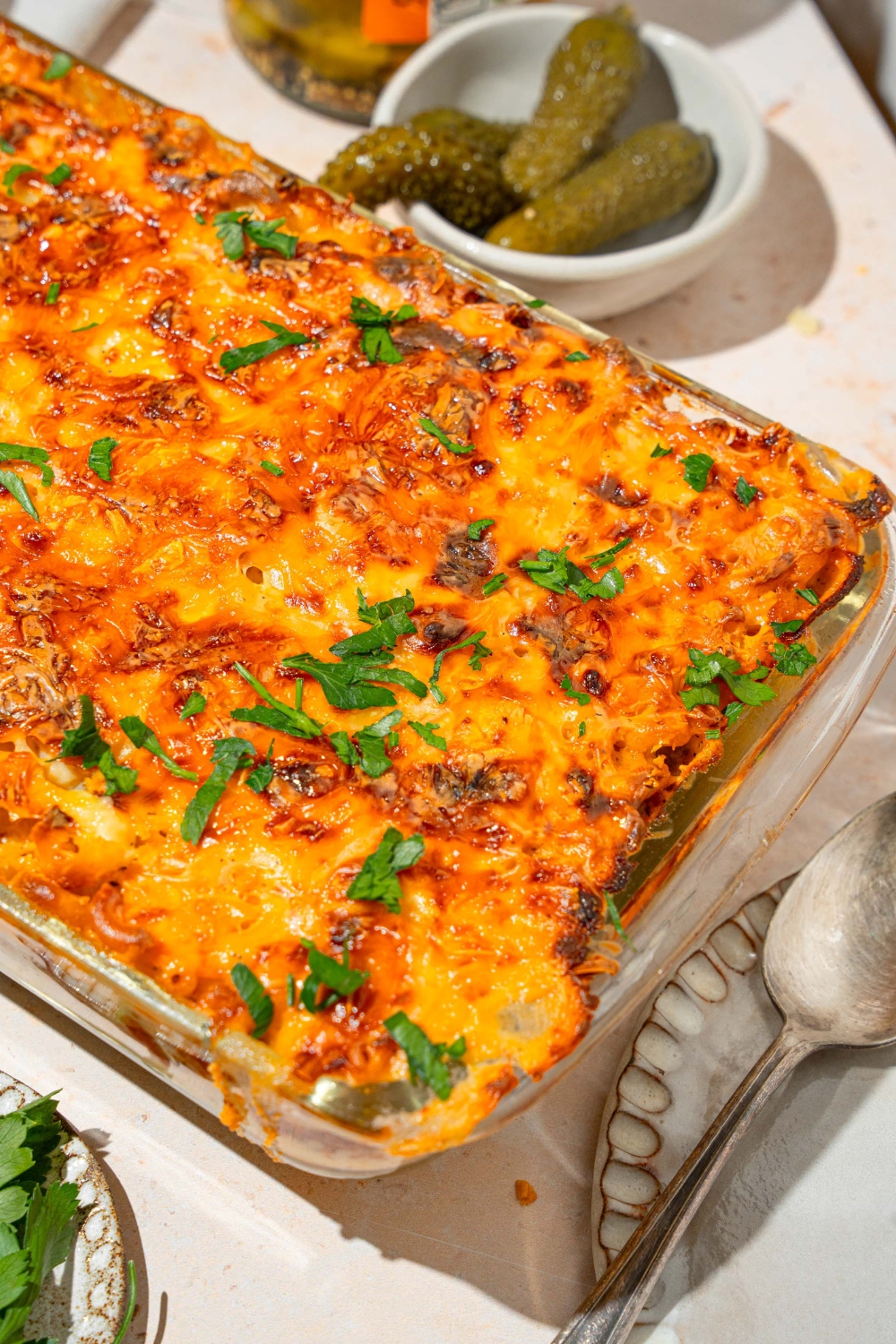 Half of a glass baking dish that is filled with mac & cheese lasagna.