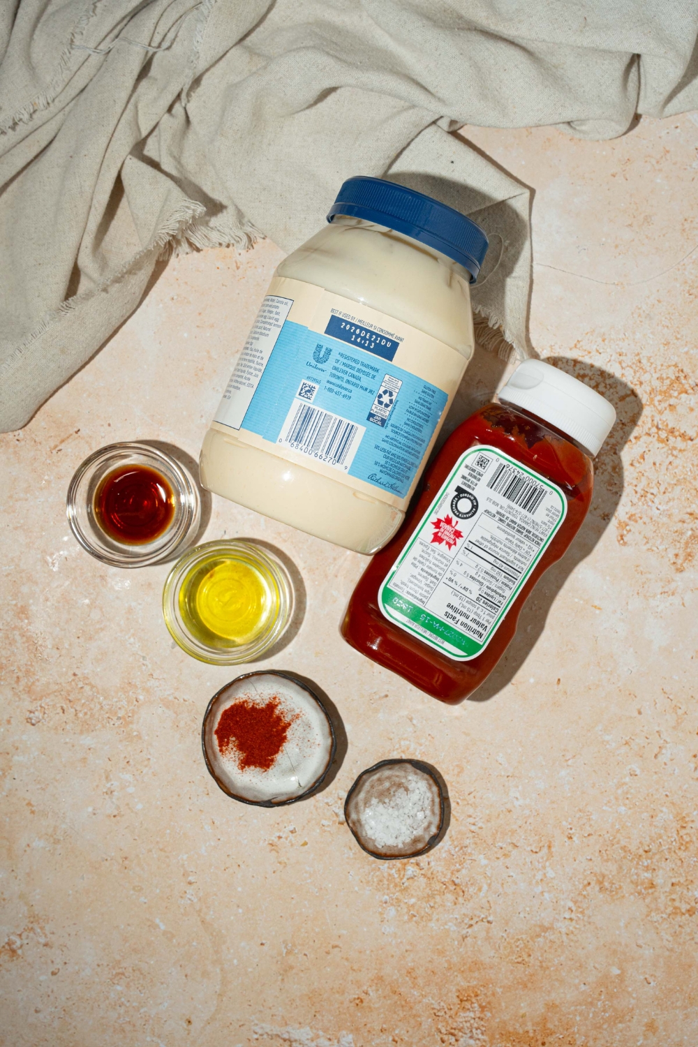 A tan counter with ingredients to make fry sauce including mayo, ketchup, pickle brine, Worcestershire sauce, and seasonings.
