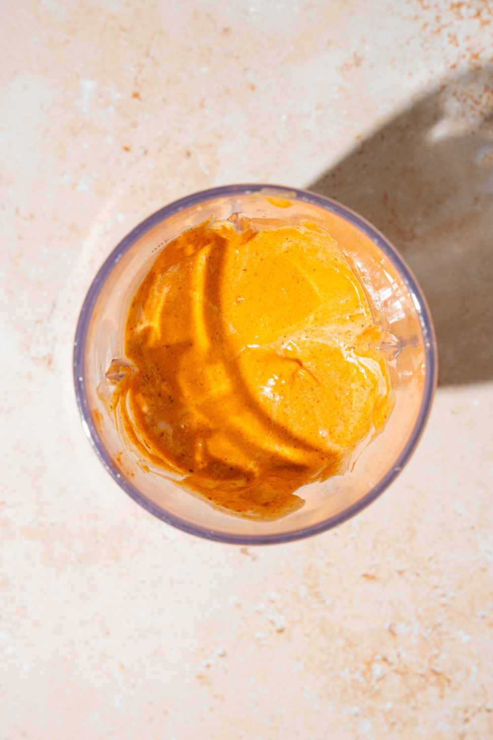 A blender jar with blended Taco Bell chipotle sauce. The jar is on a tan counter.
