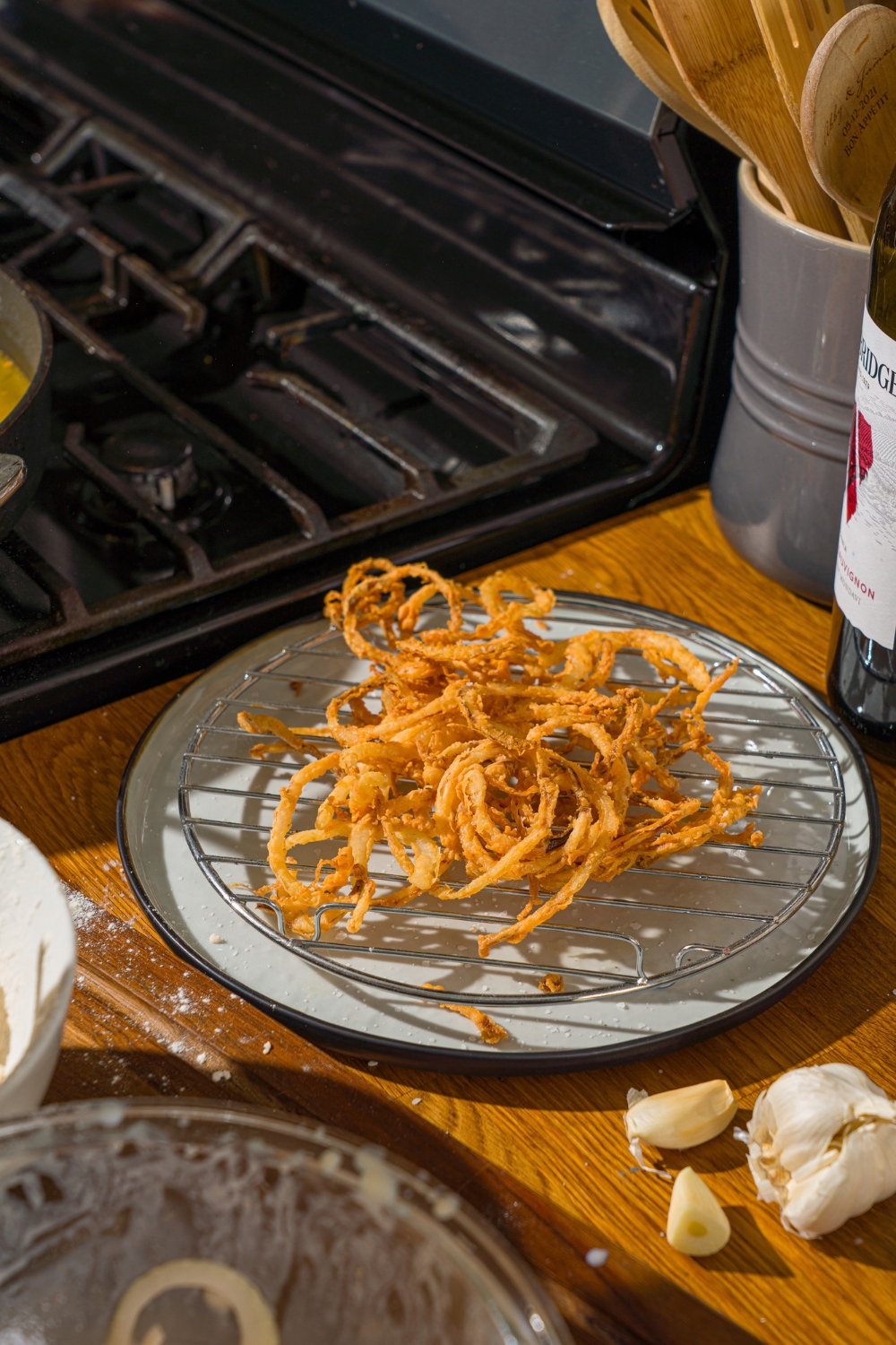 A plate lined with a wire rack with fried onions. The plate is on a wooden counter.