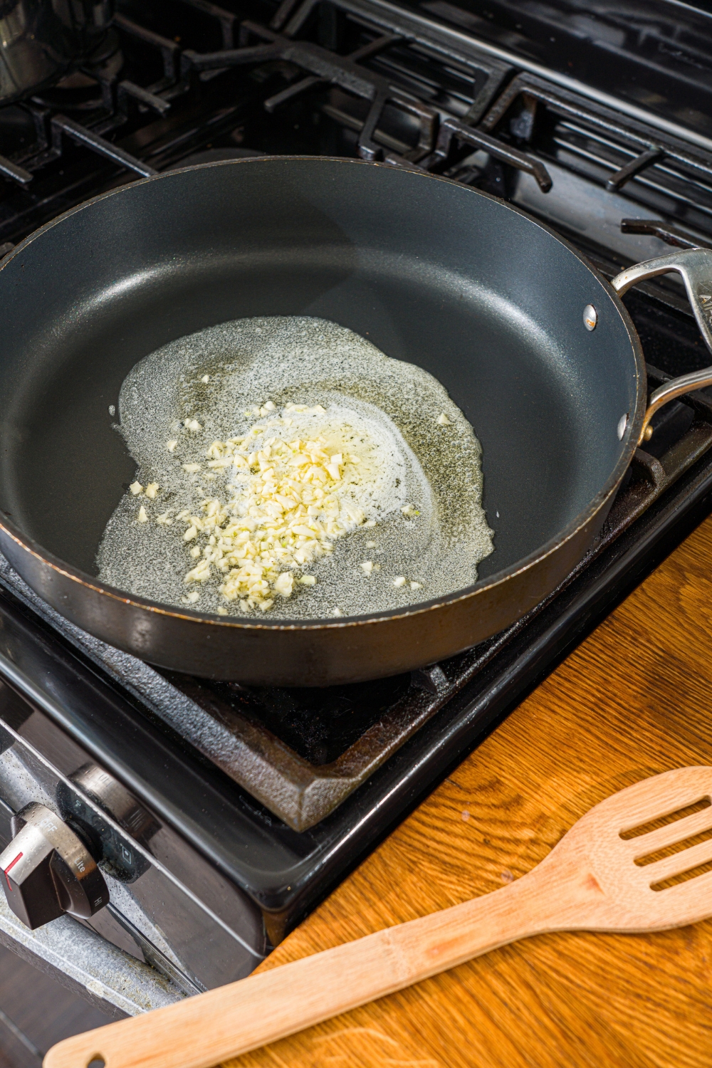 A skillet with garlic cooking in butter on the stove.