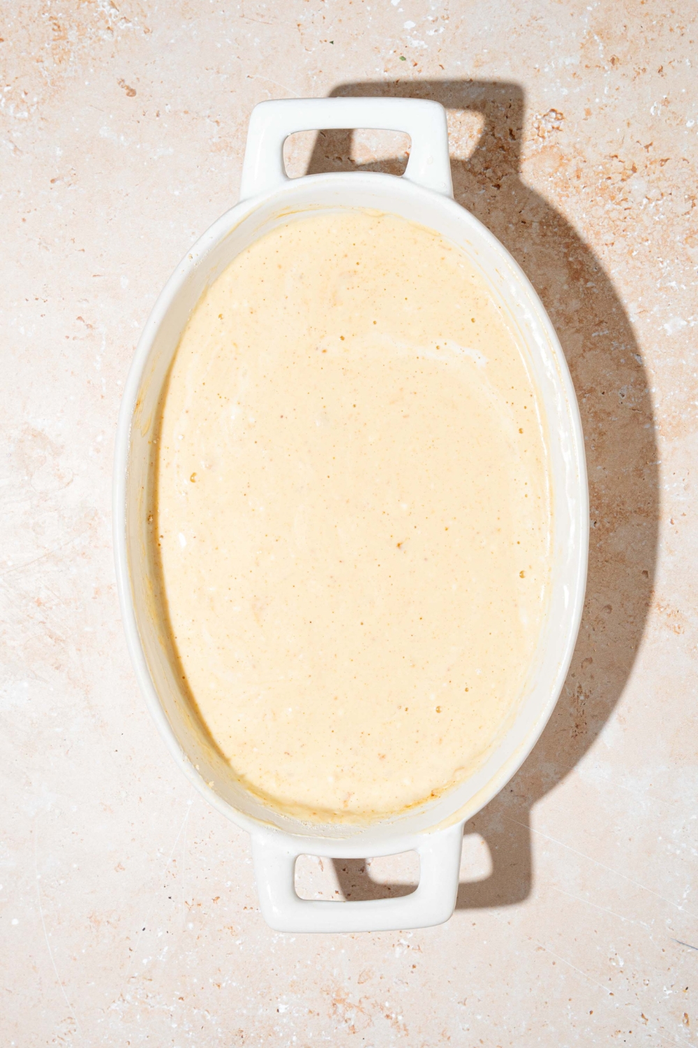An oven safe bowl with protein pancake batter. The bowl is on a tan counter.