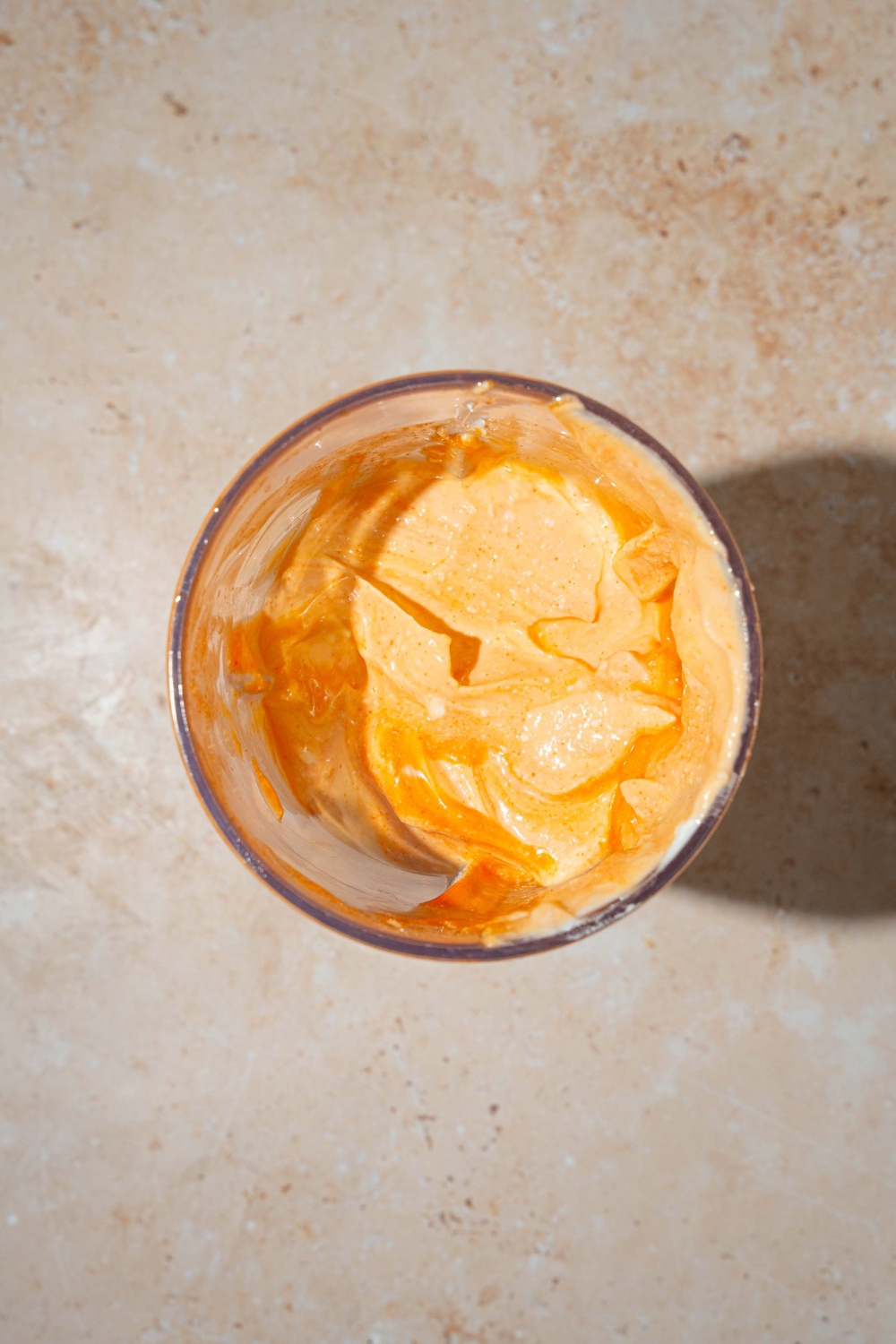 A blender jar with blended Buffalo cottage cheese. The jar is on a tan counter.