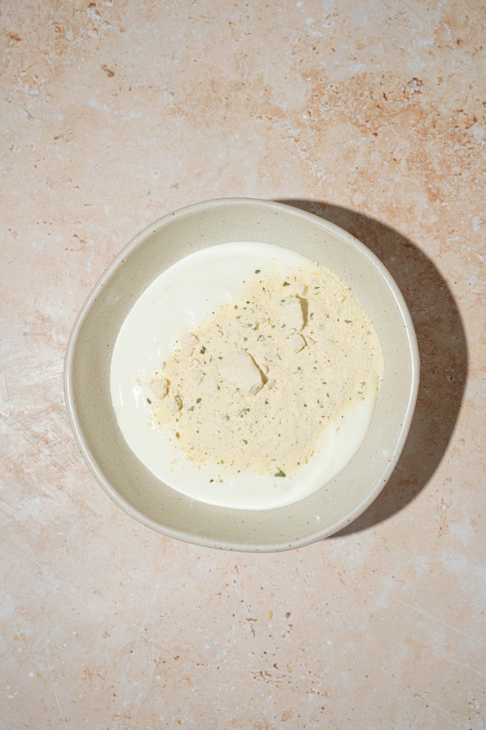 A white bowl with blended cottage cheese and ranch seasoning. The bowl is on a tan counter.