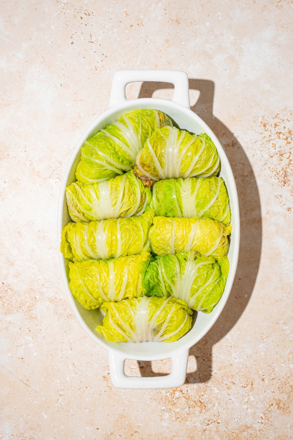 An oval baking dish with rolled cabbage dumplings. The dish is on a tan counter.