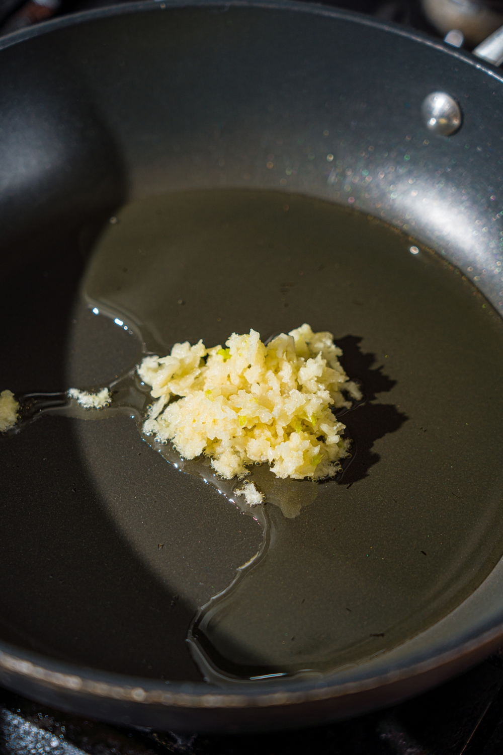 A skillet with garlic roasting in oil.