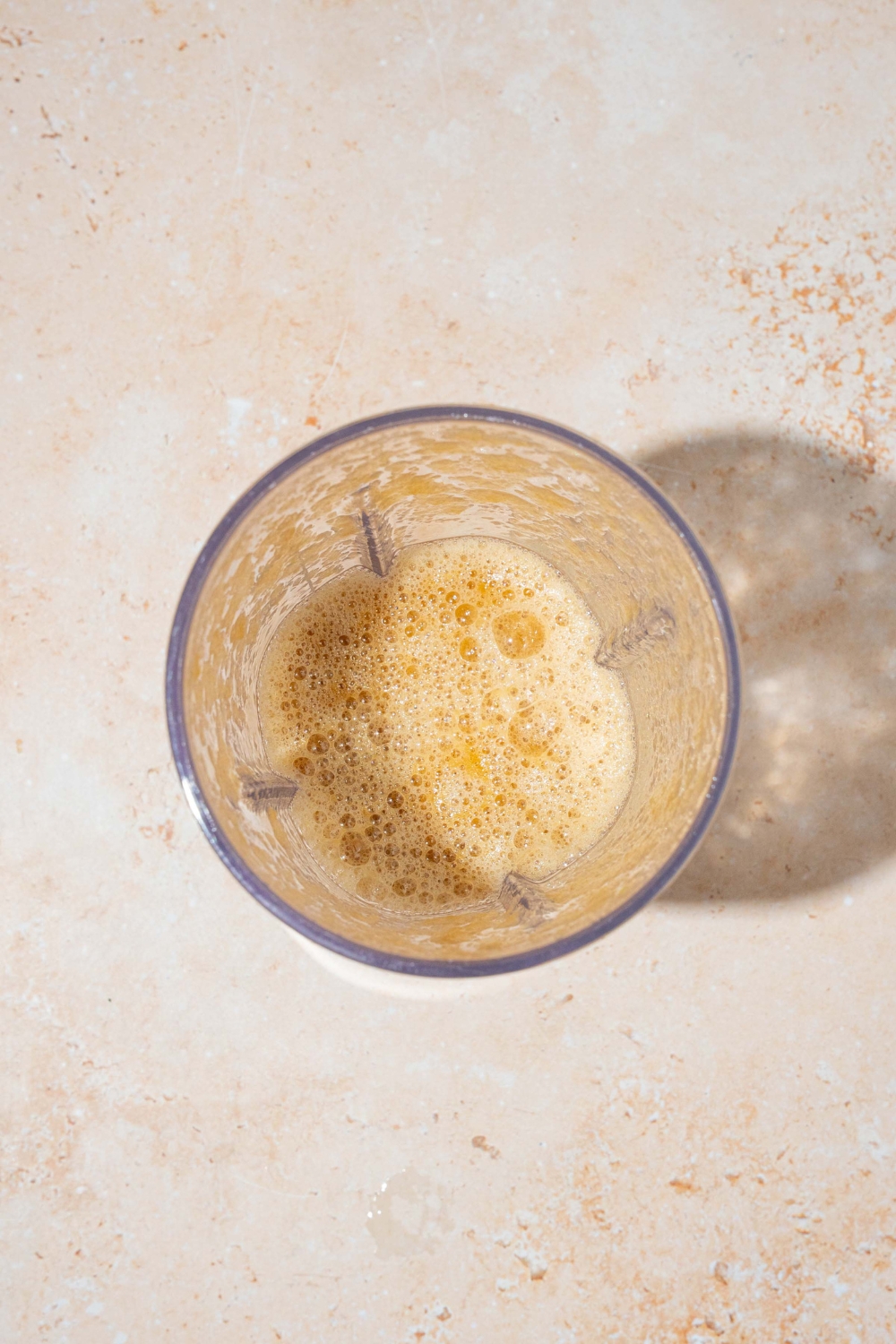 A blender jar with blended hibachi ginger sauce. The jar is on a tan counter.