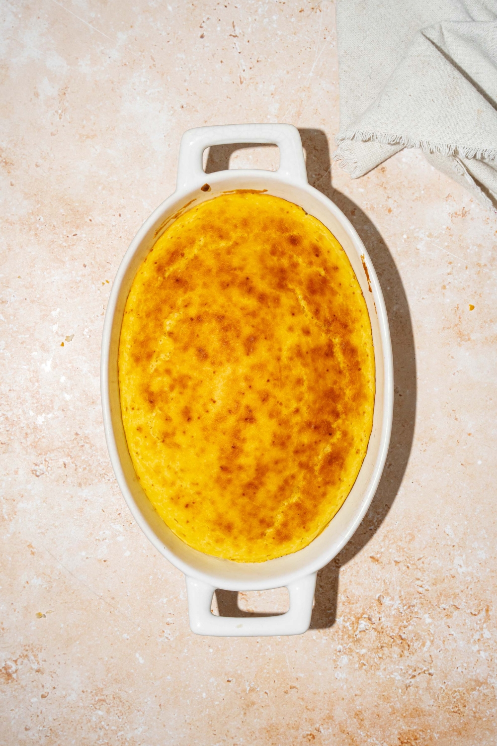 An oval baking dish with baked cornmeal without eggs. The dish is on a tan counter.