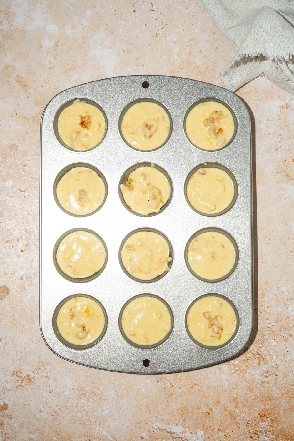 A mini muffin tin with pancake sausage batter. The tin is on a tan counter.