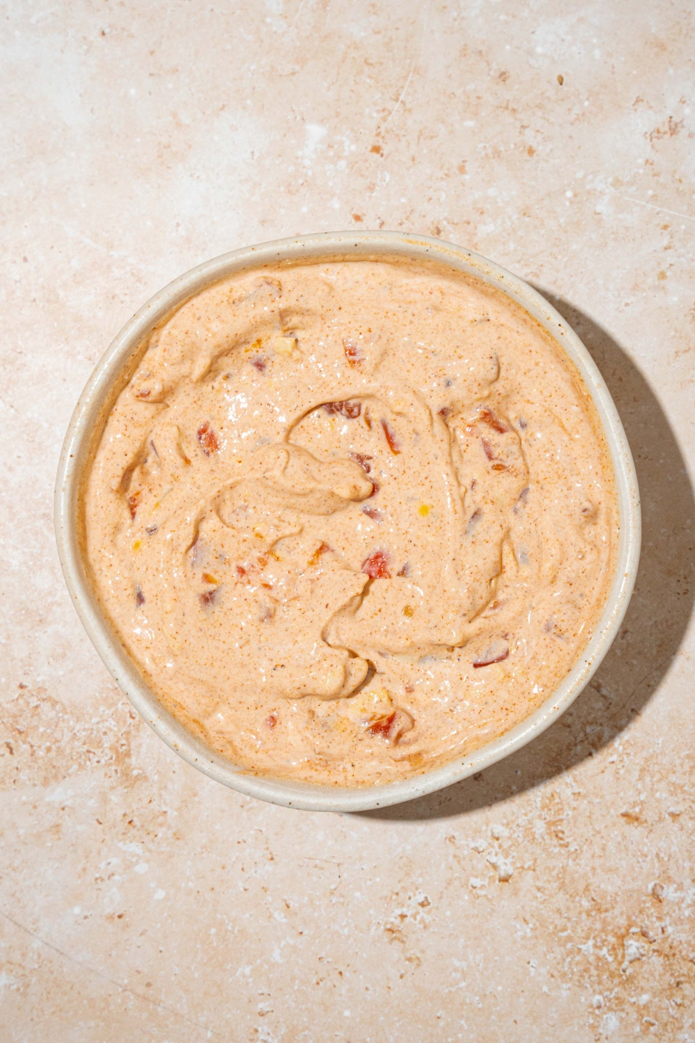A white bowl with mixed poolside dip. The bowl is on a tan counter.