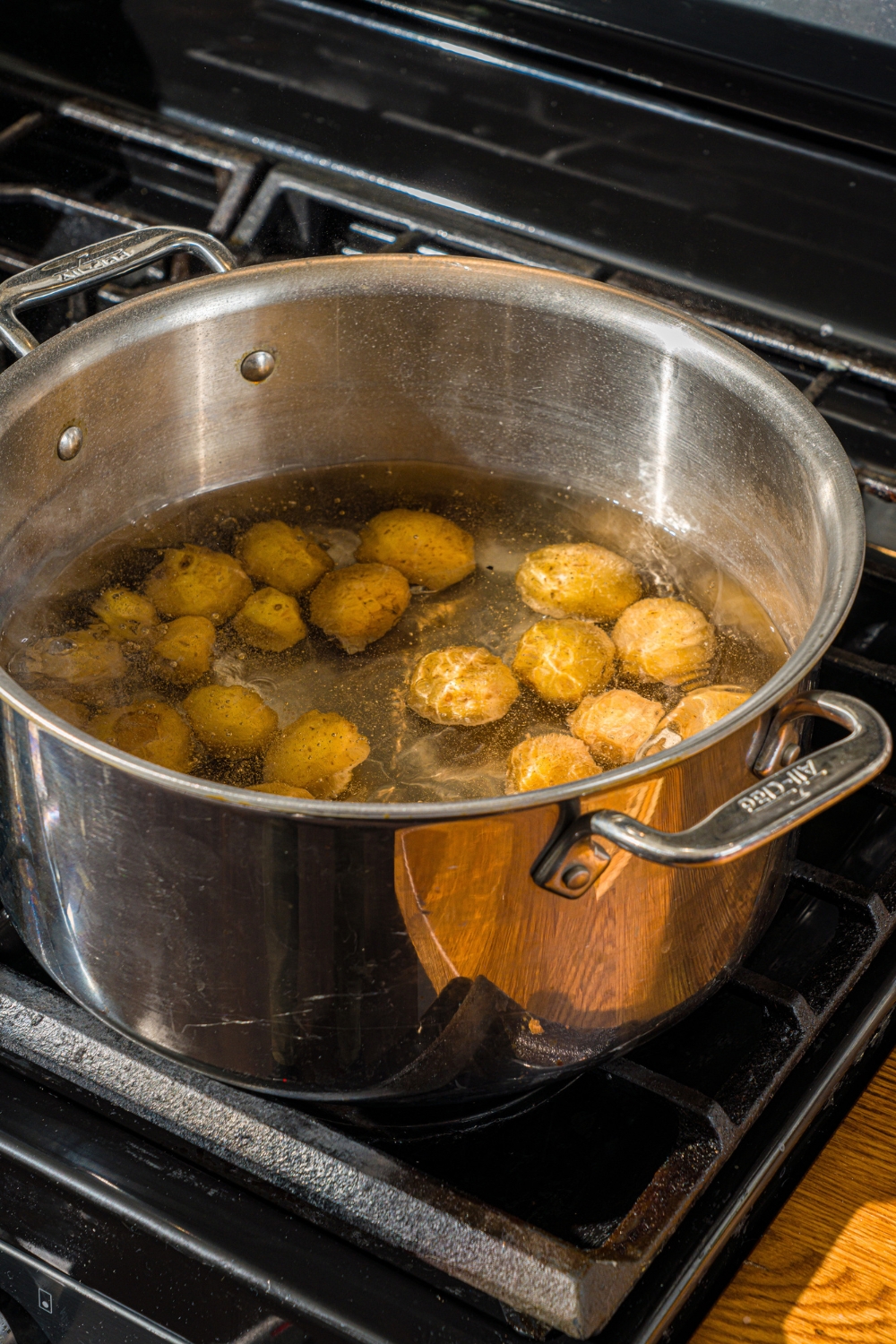 A stove with a large stock pot filled with potatoes cooking in water.