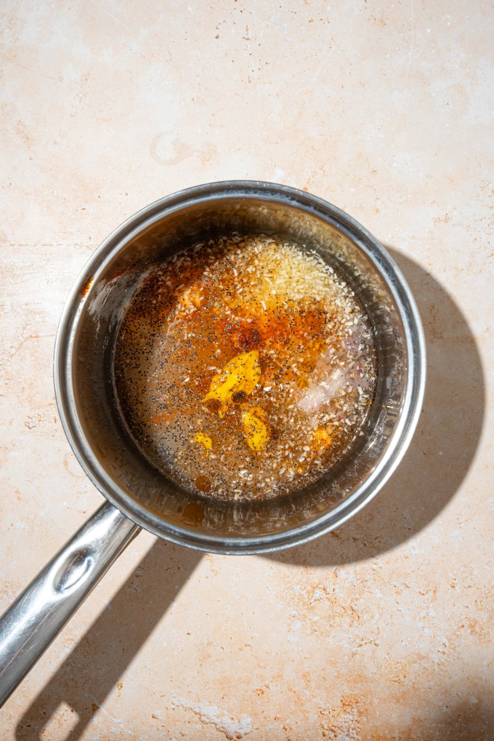 A saucepan with ingredients to make sweet onion sauce coming to a boil. The saucepan is on a tan counter.