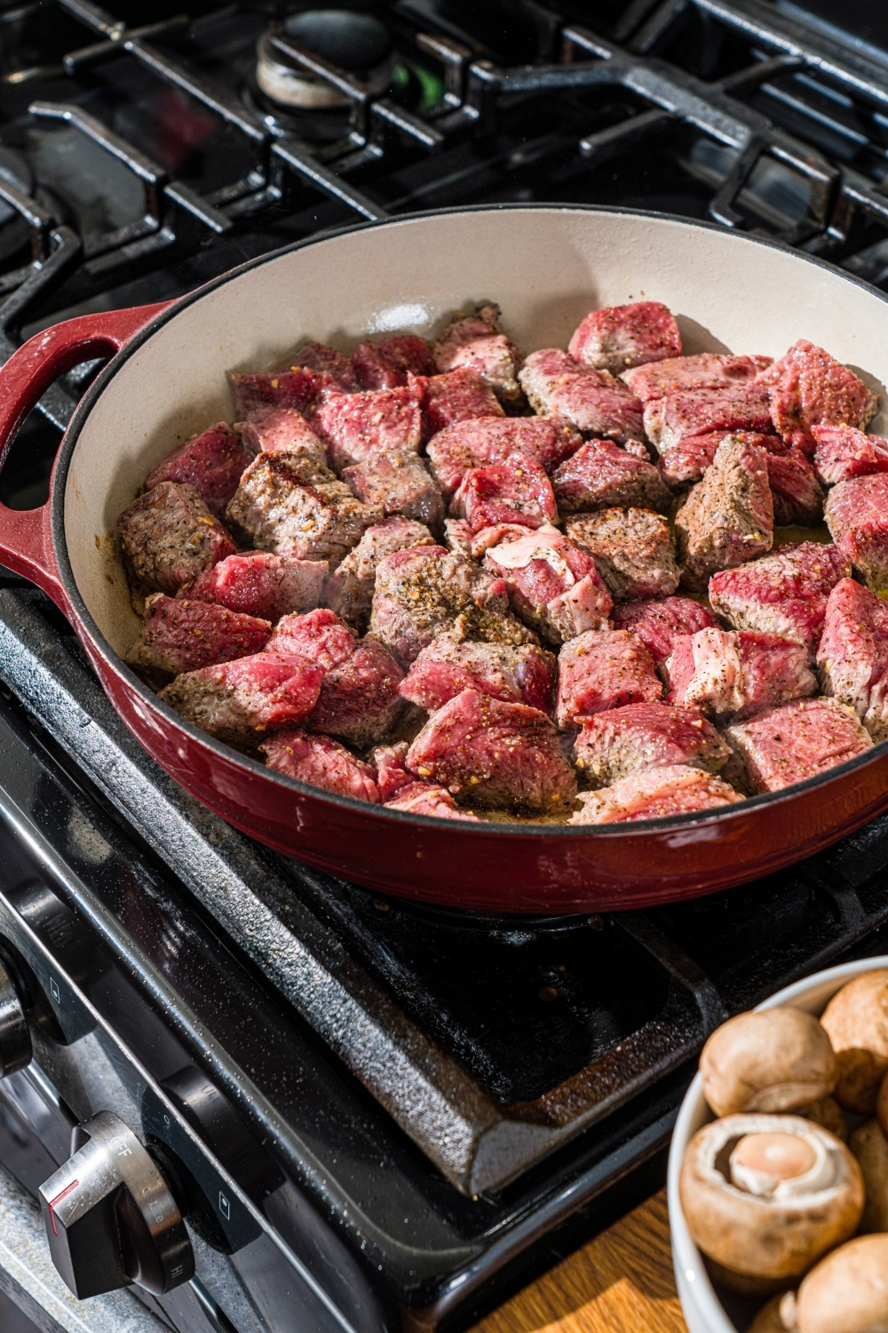 A cast iron skillet with seasoned beef tips cooking on the stove.