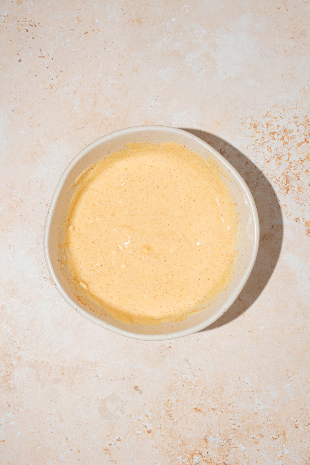 A white bowl with mixed Burger King zesty sauce. The bowl is on a tan counter.