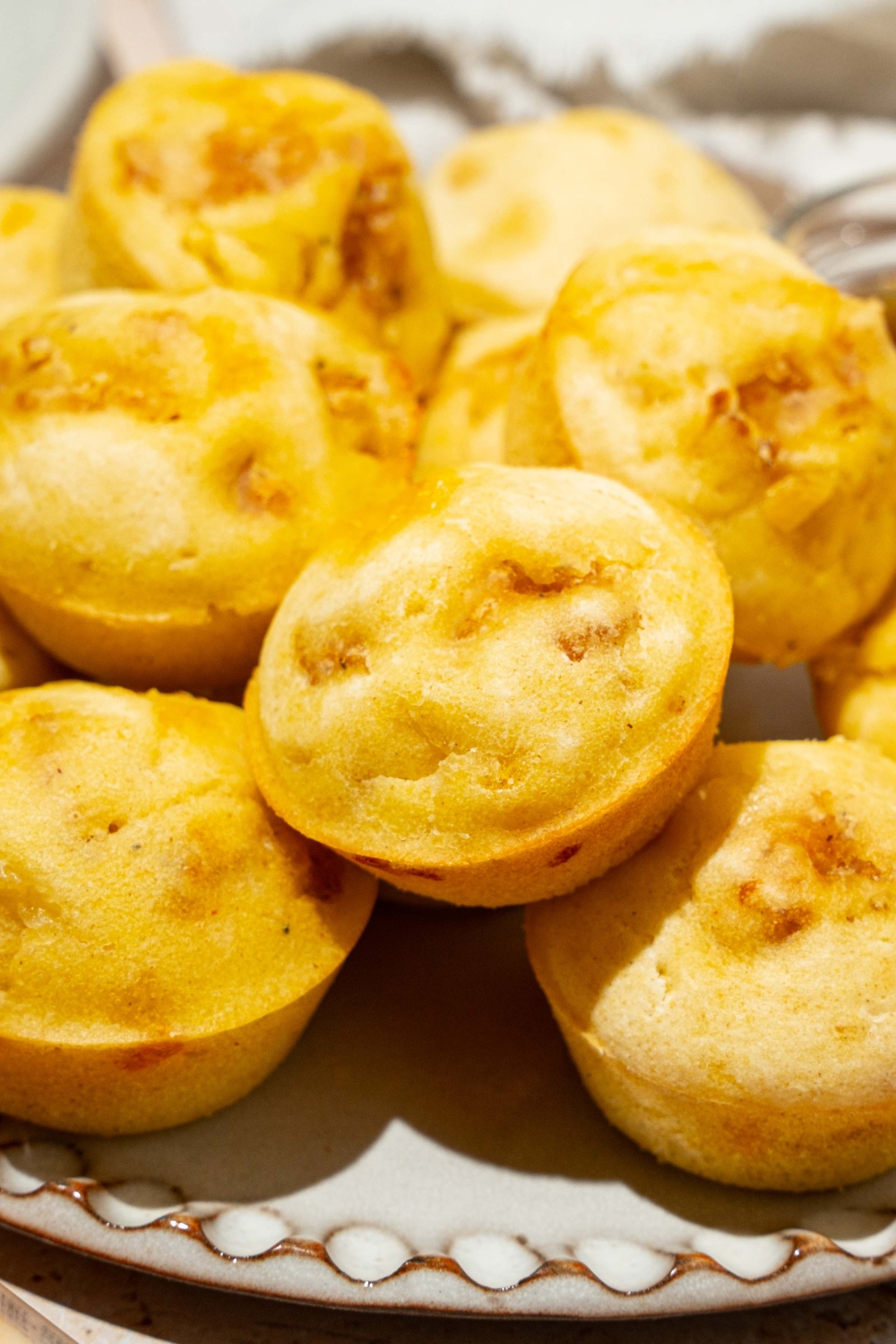 A plate with a pile of pancake sausage muffins. The plate is on a tan counter.