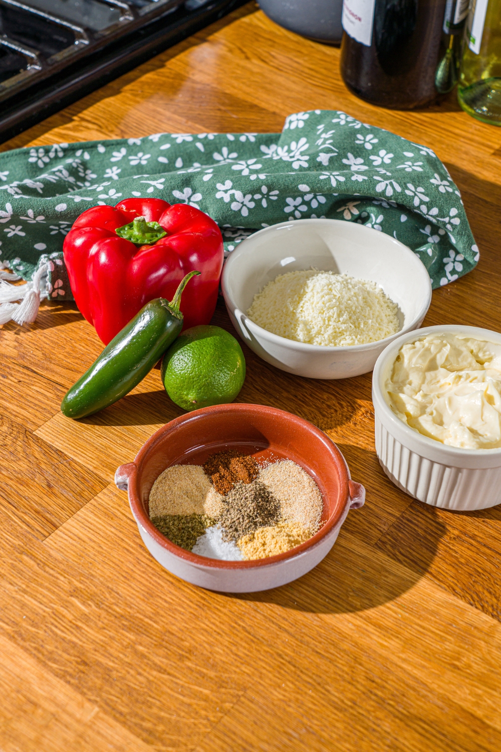 A wooden counter with bowls of ingredients to make Taco Bell baja sauce including mayo, red pepper, jalapeño, cotija cheese, lime, and seasonings.