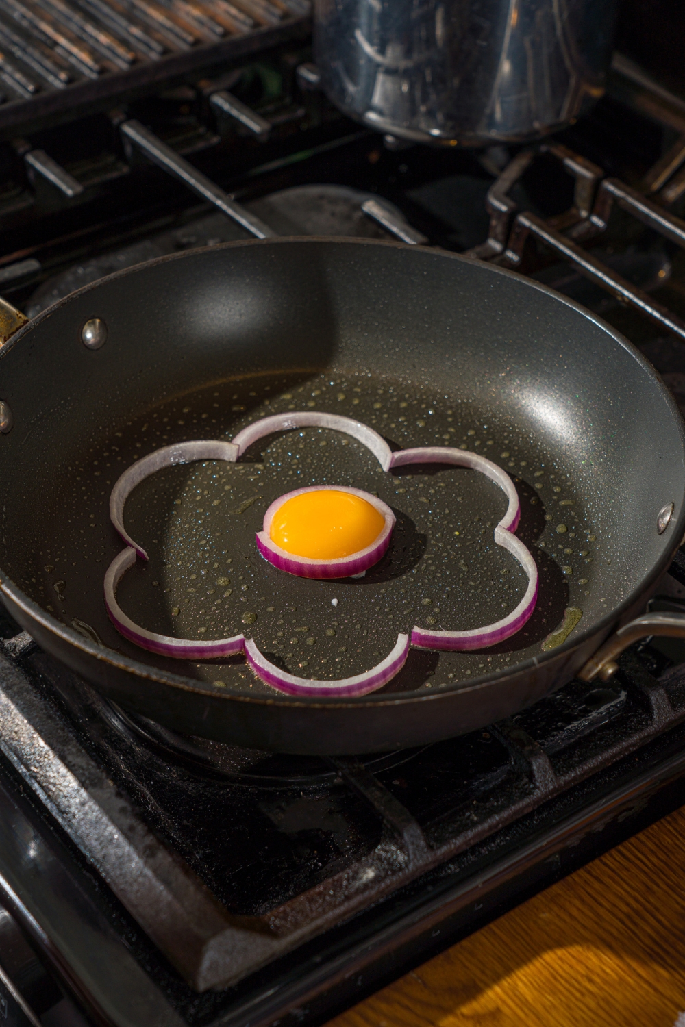 An egg yolk inside a flower shape in a skillet.