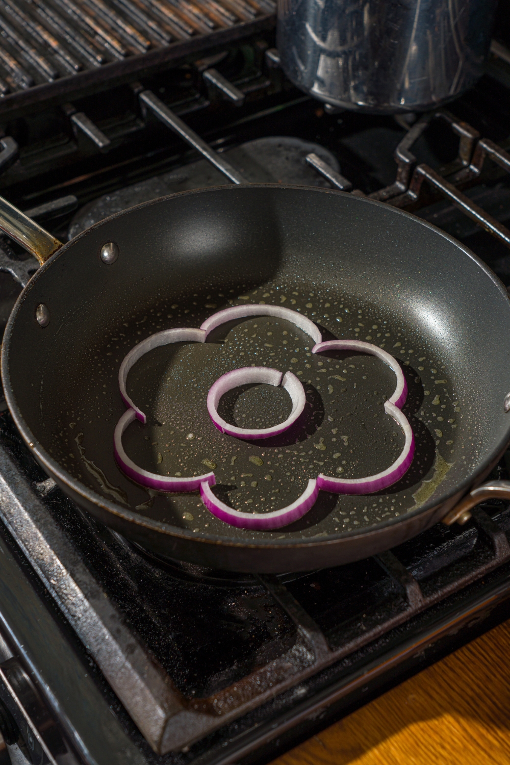 A flower shape made out of an onion in a skillet.